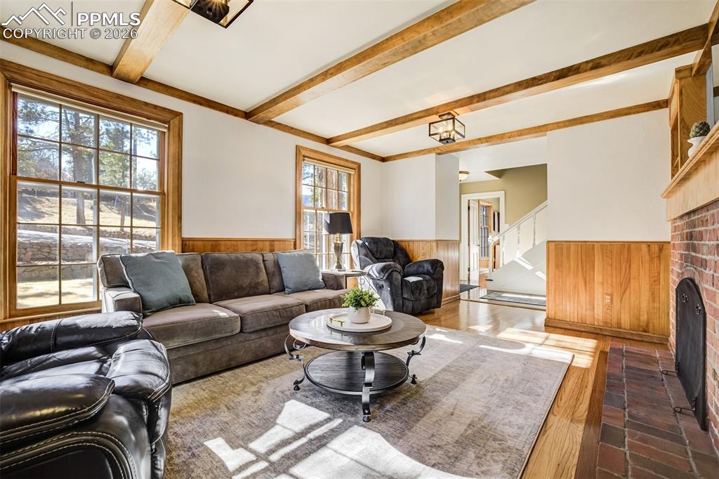 Image 8 of 50: Main level living area with wood wainscoted wall, built in features, a fire