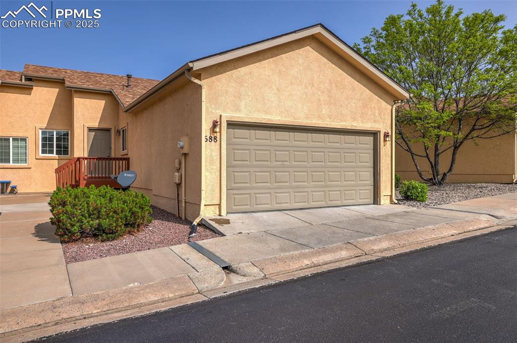 Caption: View of front of house with stucco siding, an attached 2 car garage, and concrete driveway