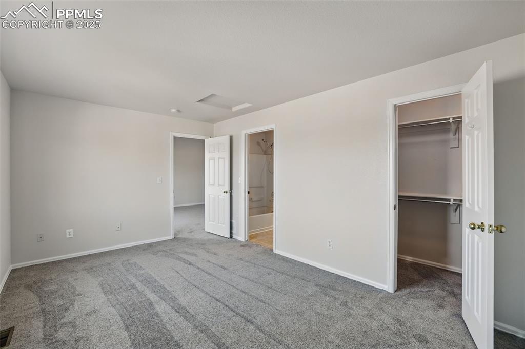 Image 26 of 50: Unfurnished bedroom featuring carpet floors, a spacious closet, baseboards,
