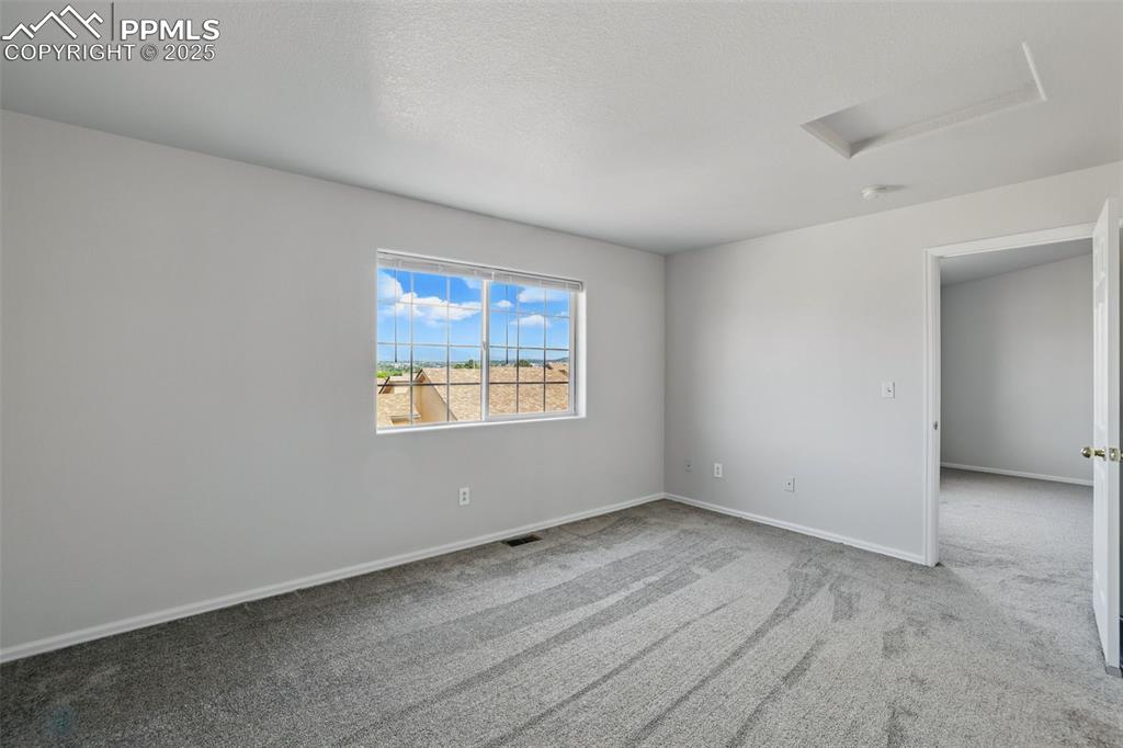 Image 27 of 50: Empty room featuring attic access, carpet, baseboards, and a smoke detector