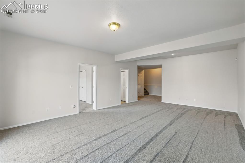 Image 41 of 50: Unfurnished room with light carpet, baseboards, and stairs