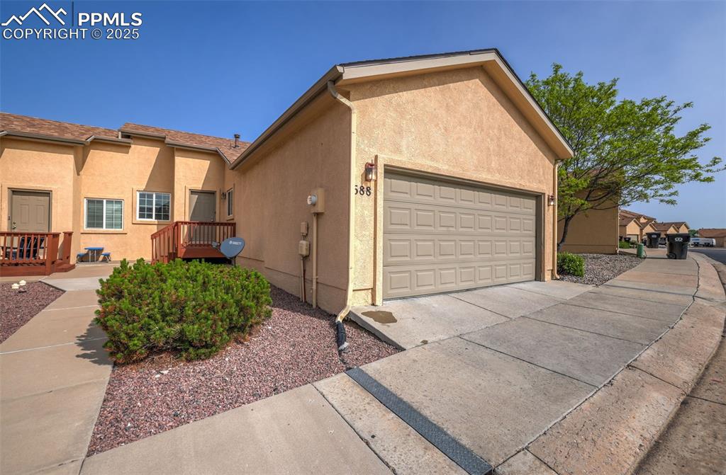 Image 6 of 50: View of side of property with stucco siding and an attached 2 car garage