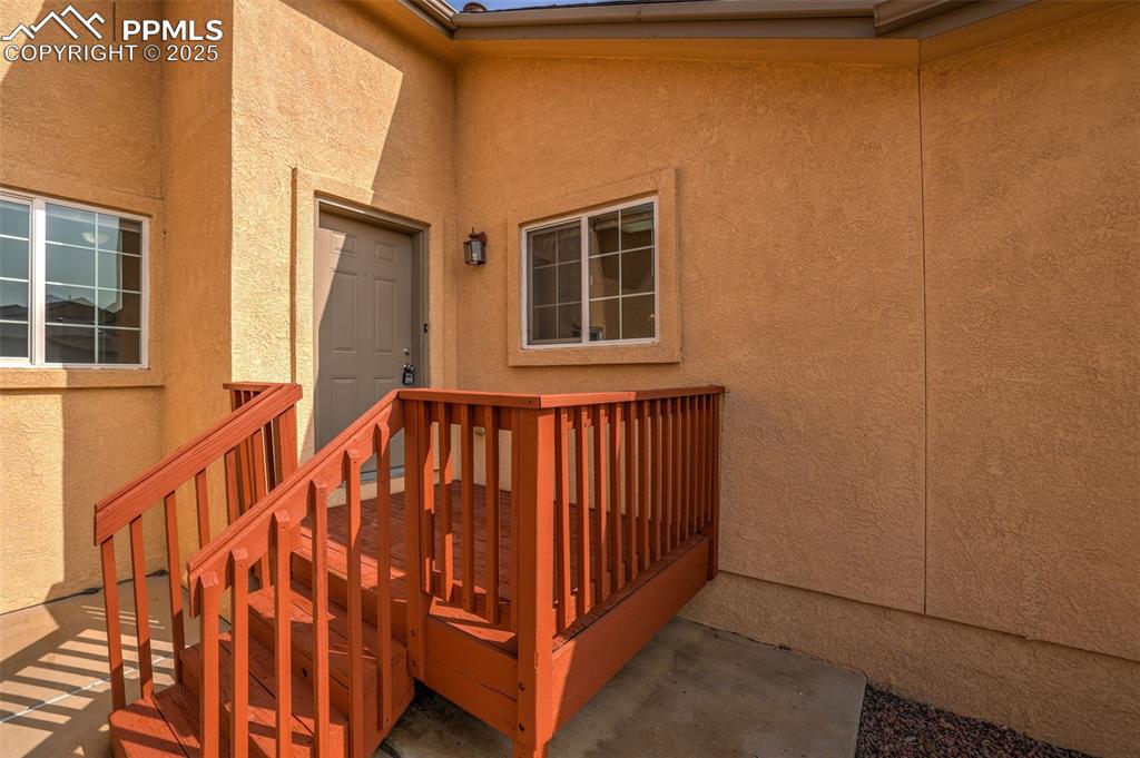 Image 7 of 50: Property entrance with stucco siding & wood deck entry
