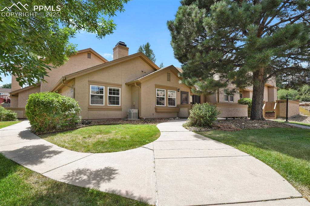 Image 1 of 23: View of front of home with stucco siding, a chimney, and a front lawn