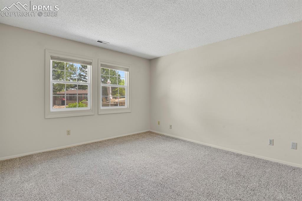 Image 11 of 23: Carpeted empty room featuring a textured ceiling and baseboards