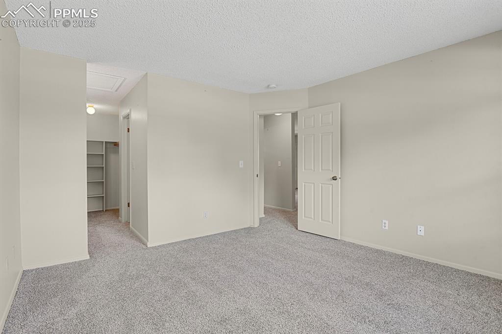 Image 12 of 23: Spare room with carpet floors, a textured ceiling, and attic access