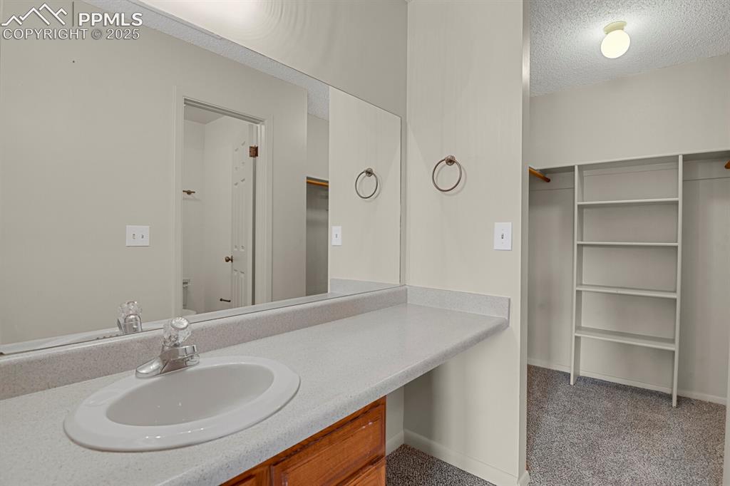 Image 13 of 23: Bathroom with a spacious closet, a textured ceiling, and vanity
