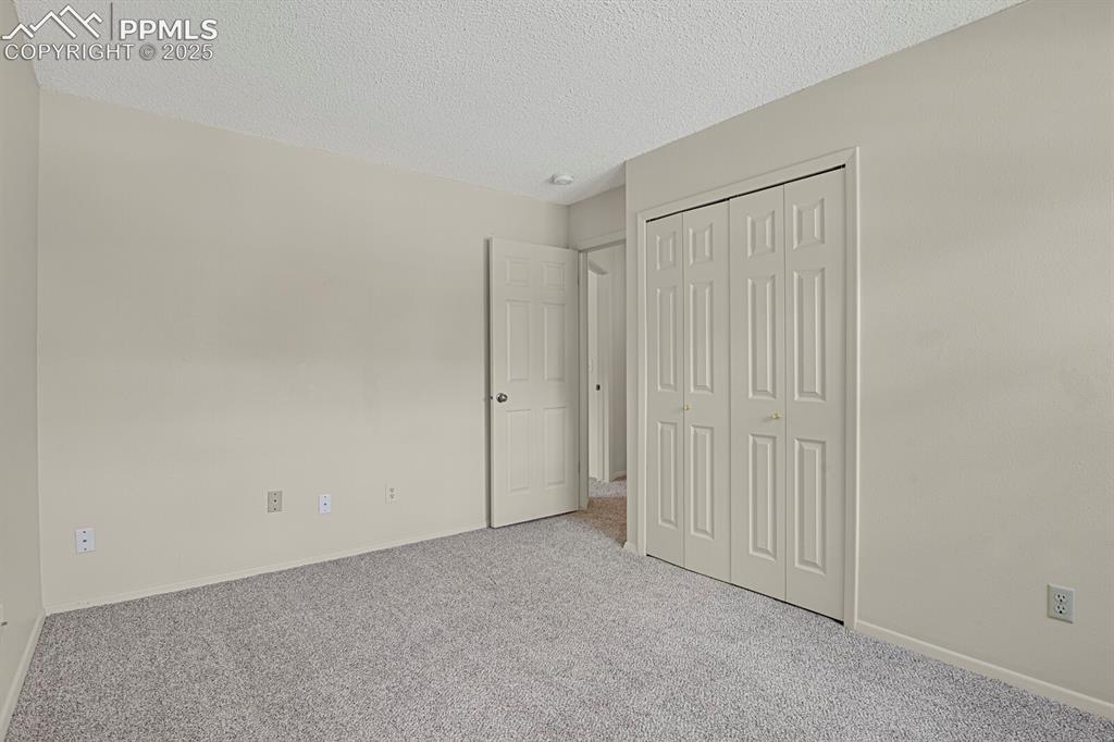 Image 16 of 23: Unfurnished bedroom with a textured ceiling, carpet flooring, and a closet