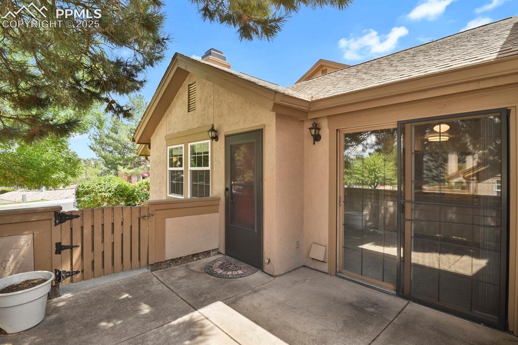Image 20 of 23: Doorway to property with a gate, stucco siding, a chimney, and a patio