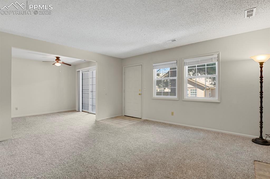 Image 5 of 23: Unfurnished living room with light carpet, a textured ceiling, and ceiling