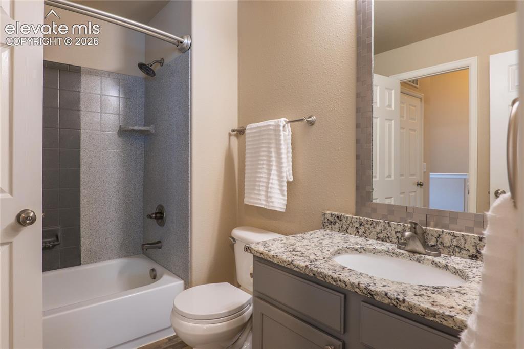 Image 13 of 18: Upper full bath with granite counter and LVP flooring.