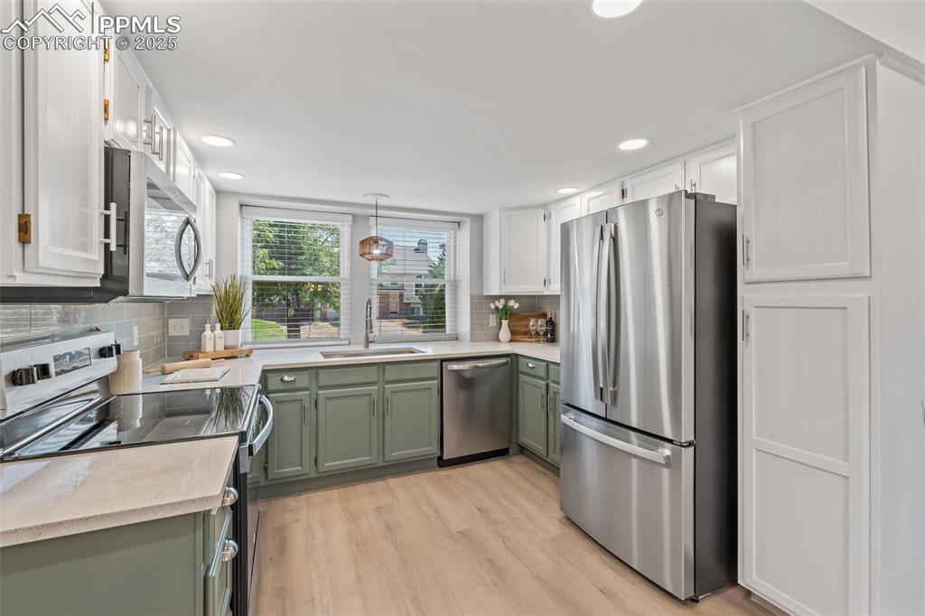 Image 11 of 40: Kitchen featuring green cabinets, appliances with stainless steel finishes,