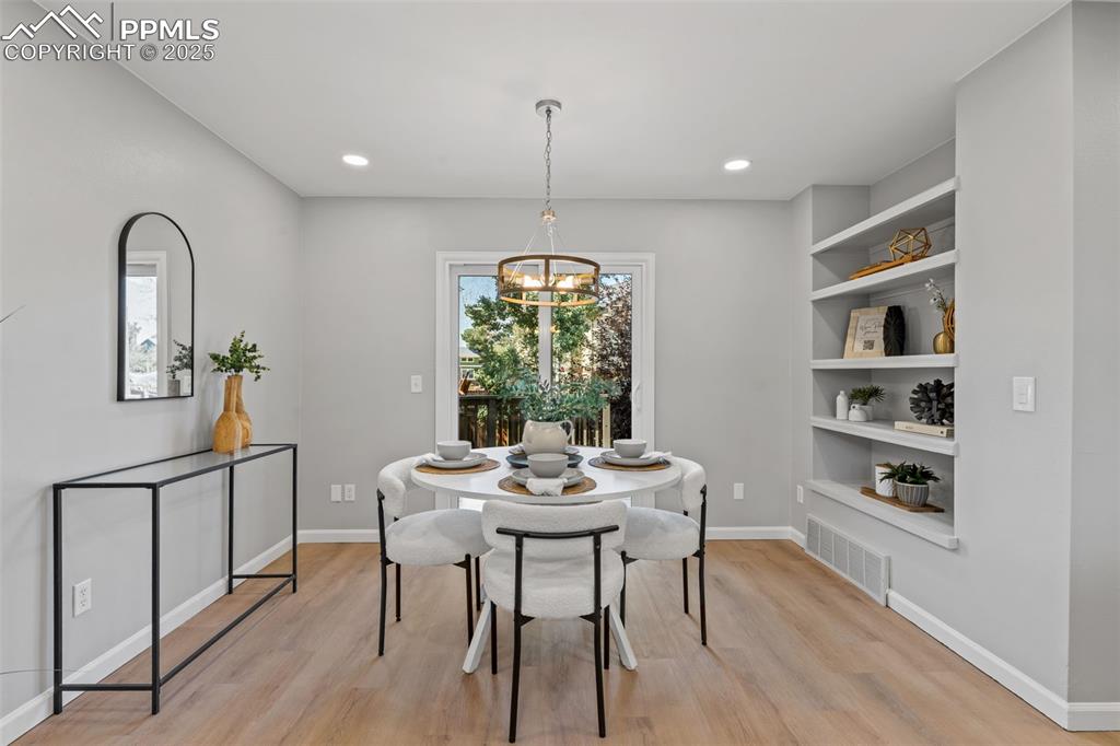 Image 15 of 40: Dining room with light wood-style floors, a chandelier, built in features, 