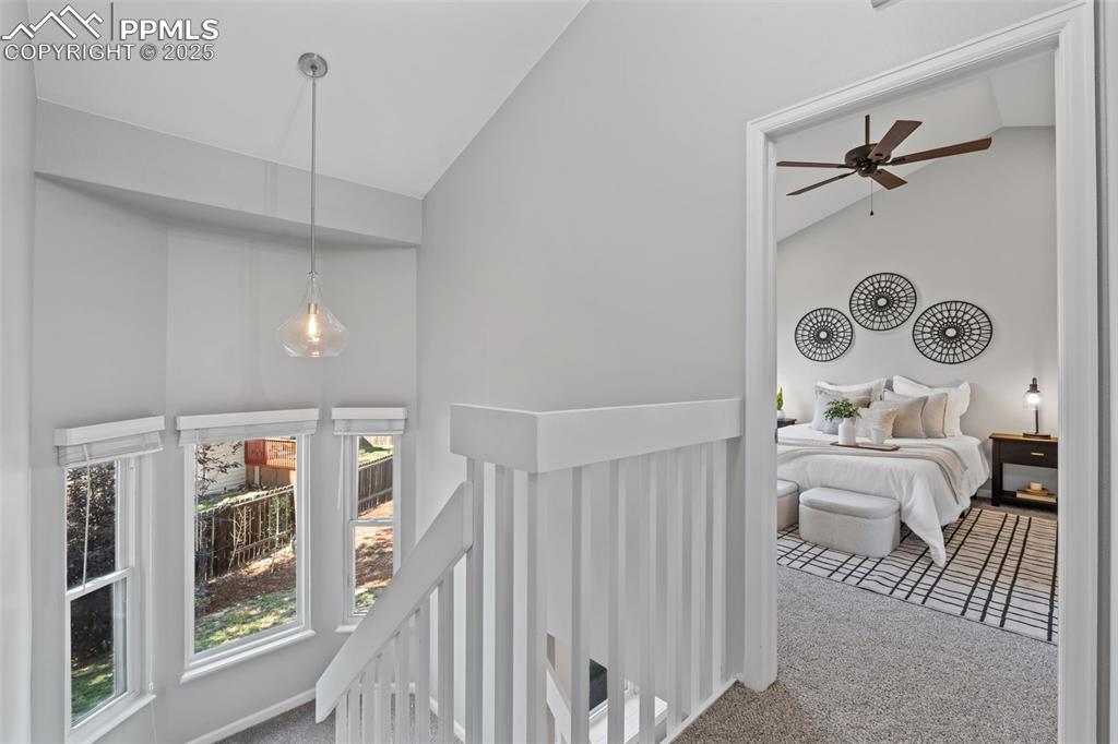 Image 19 of 40: Hallway featuring high vaulted ceiling, carpet flooring, and an upstairs la