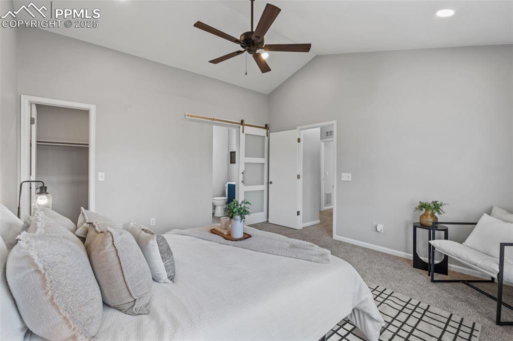 Image 21 of 40: Carpeted bedroom featuring a barn door, a spacious closet, a ceiling fan, a