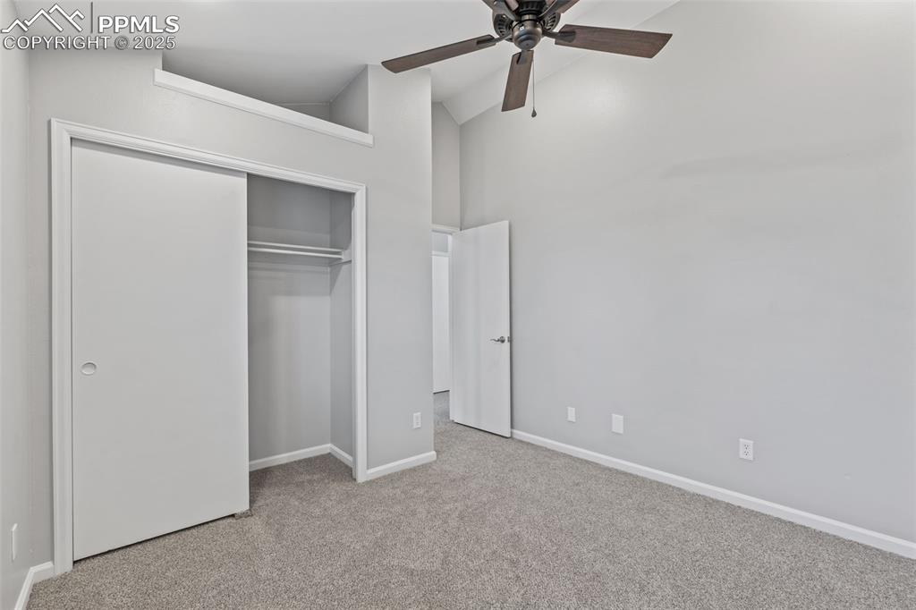 Image 29 of 40: Unfurnished bedroom with light carpet, high vaulted ceiling, ceiling fan, a