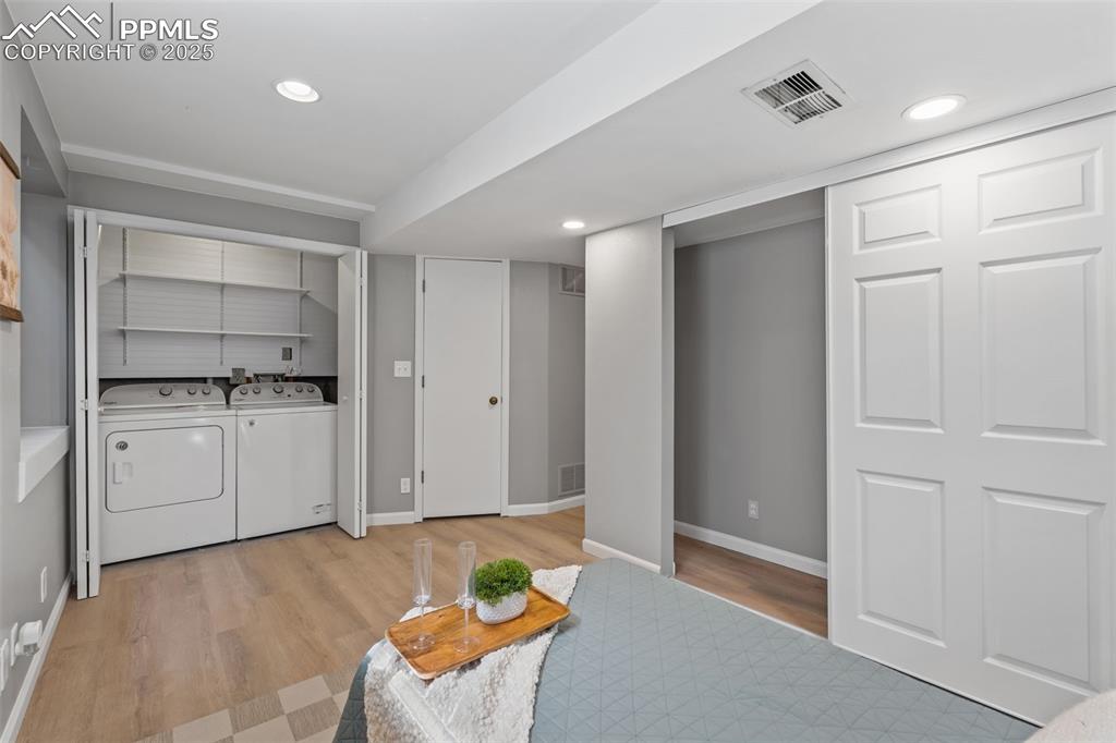 Image 31 of 40: Laundry room featuring independent washer and dryer, light wood-style floor