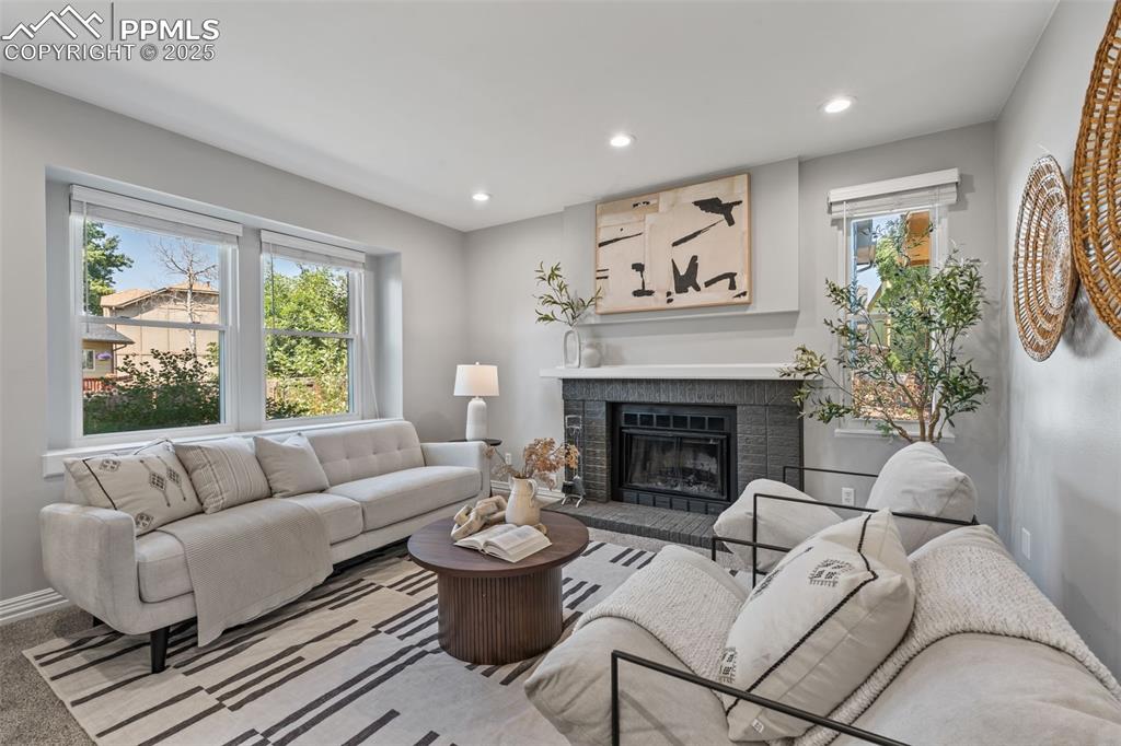 Image 5 of 40: Living area with a brick fireplace, recessed lighting, and carpet