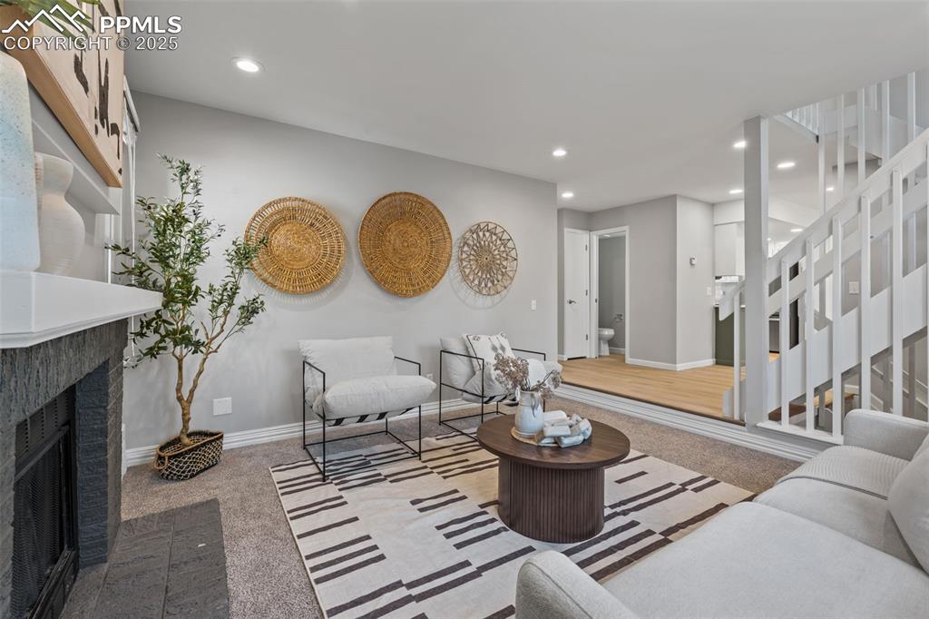 Image 8 of 40: Living area with carpet, a tiled fireplace, recessed lighting, and stairway