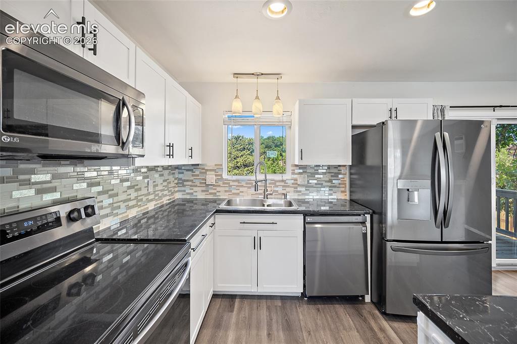 Image 10 of 50: Kitchen with white cabinetry and tile backsplash.
