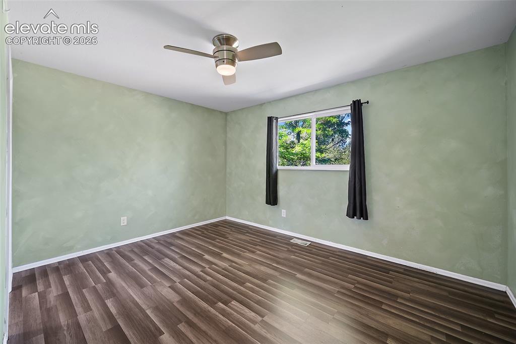 Image 16 of 50: Bedroom with ceiling fan and updated flooring.