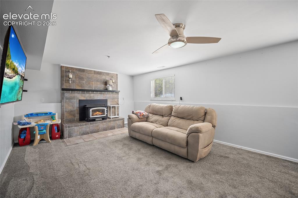 Image 25 of 50: Family room with fireplace and ceiling fan.