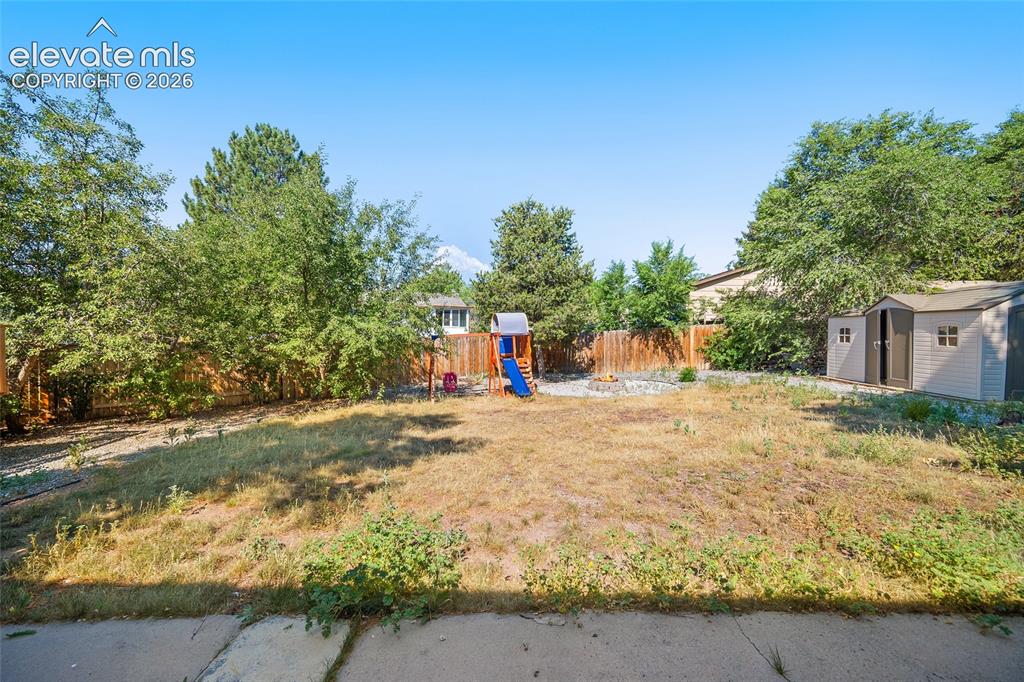 Image 32 of 50: Fenced backyard with storage shed.
