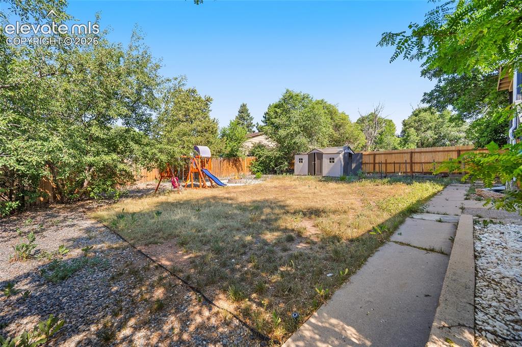 Image 33 of 50: Private backyard with mature trees and open lawn.