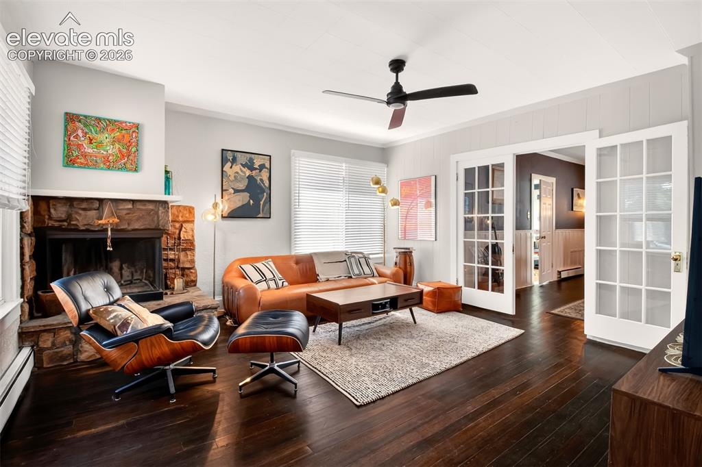 Image 5 of 30: Living room with a stone fireplace and French doors leading to the dining r