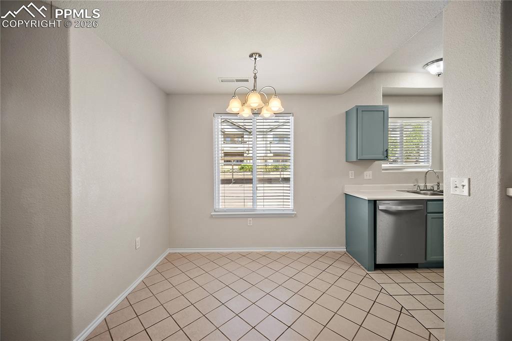 Image 10 of 31: Dining space featuring tile flooring, a multi-light chandelier, and a windo