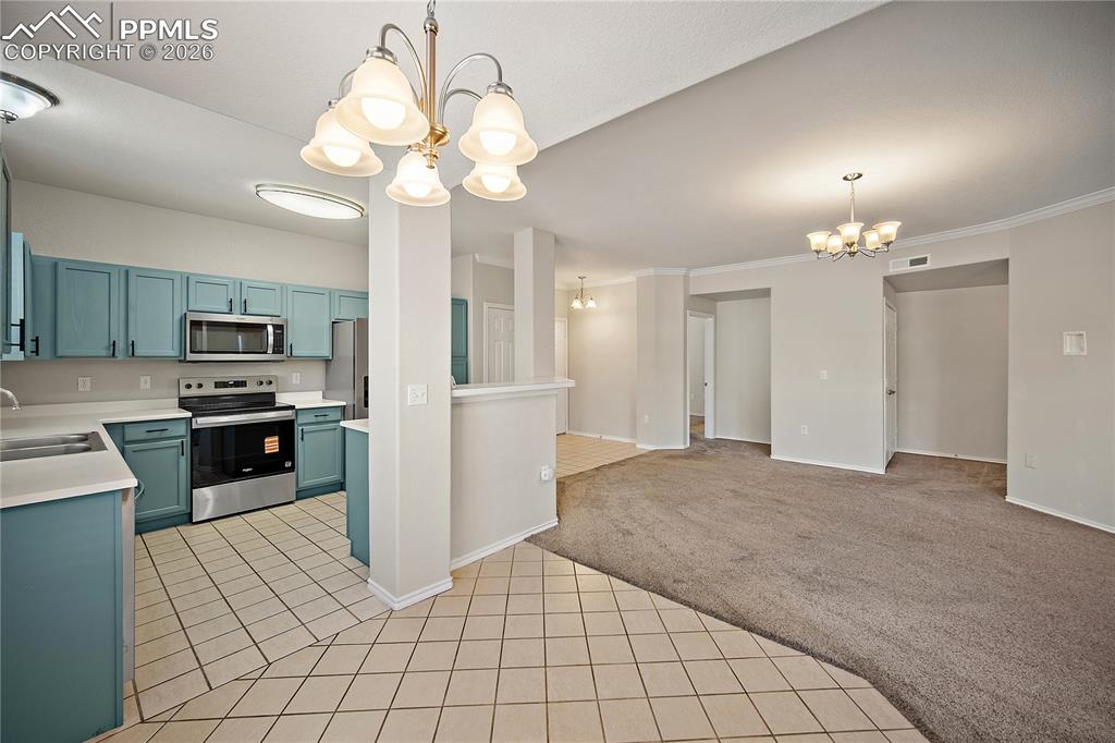 Image 12 of 31: Kitchen featuring teal cabinetry, stainless steel appliances, and tile floo