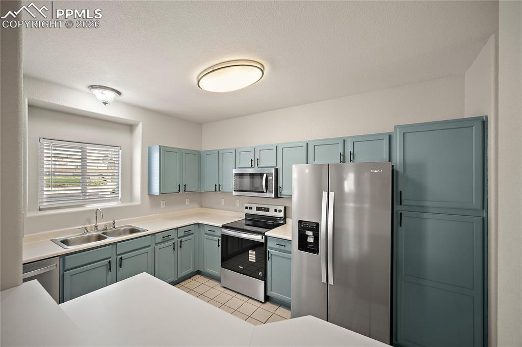 Image 17 of 31: Kitchen featuring light blue cabinetry with dark hardware, stainless steel 
