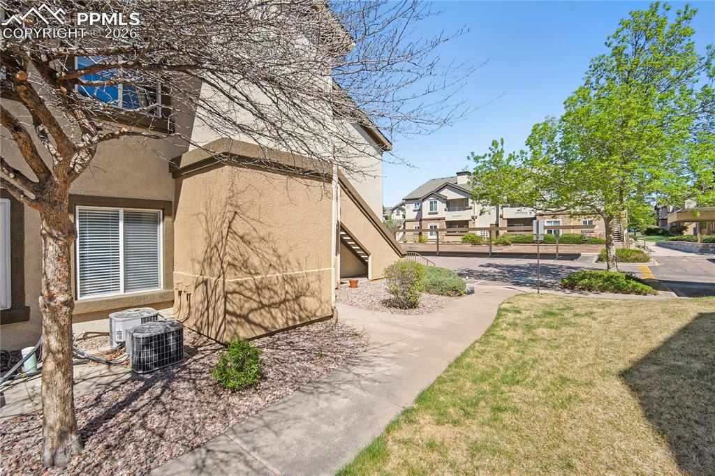 Image 2 of 31: Exterior stucco finish with multiple windows, mature trees, a concrete path