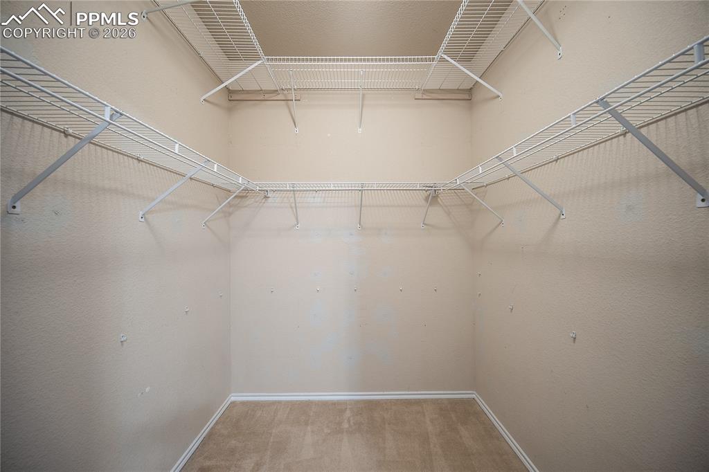 Image 20 of 31: Spacious walk-in closet featuring light beige walls, white wire shelving, a