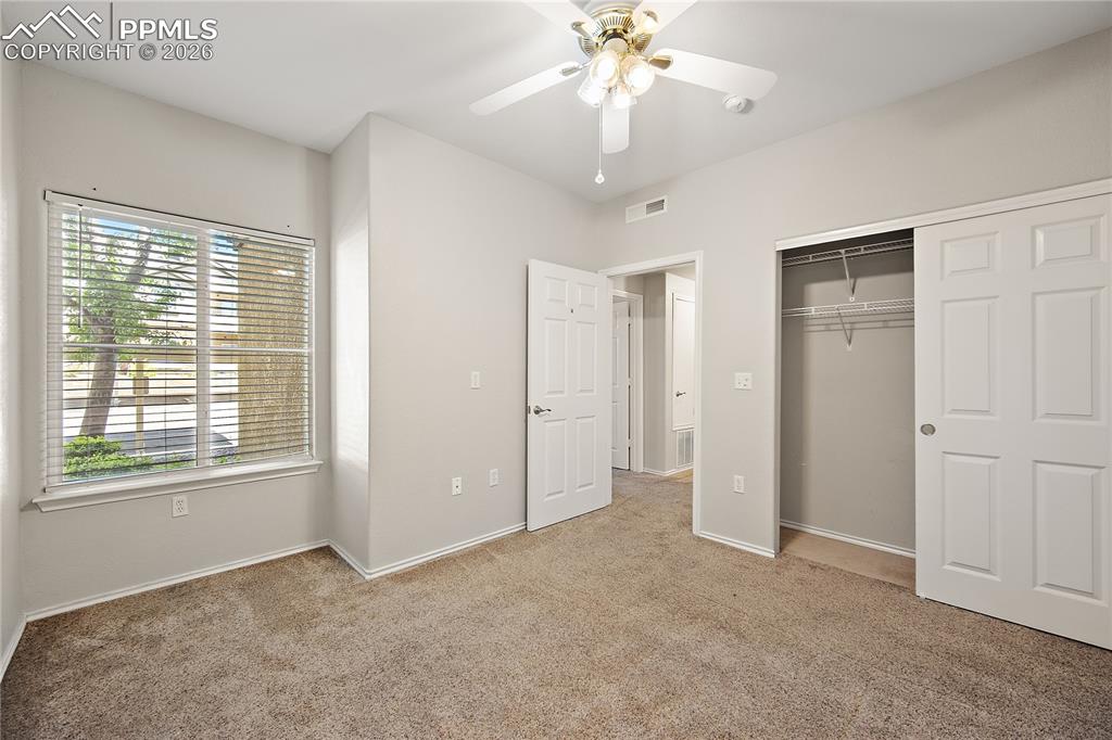 Image 27 of 31: Carpeted room featuring a large window with horizontal blinds, a ceiling fa