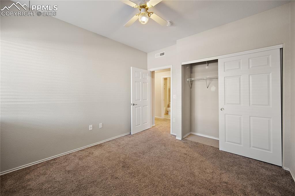 Image 29 of 31: Neutral-toned bedroom featuring plush carpet flooring, a ceiling fan with i
