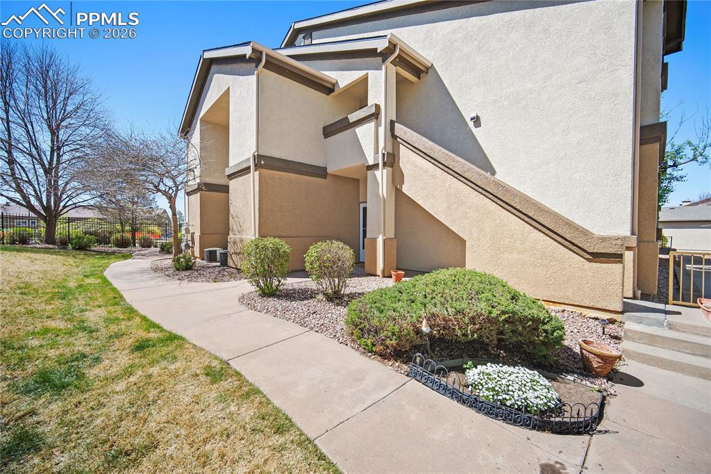 Image 3 of 31: Stucco exterior featuring multiple tones, a concrete pathway, landscaped ro