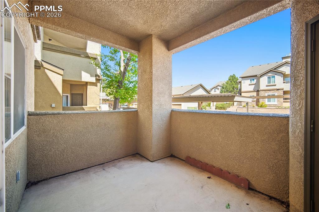 Image 30 of 31: Private balcony with stucco walls and concrete flooring, featuring a partia