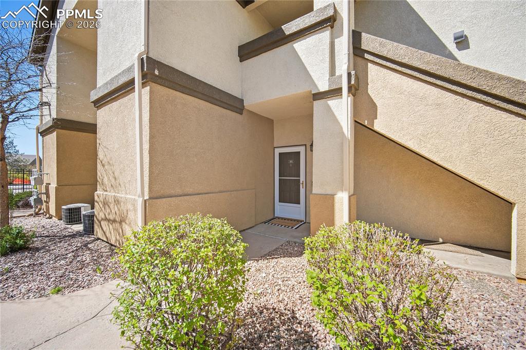 Image 4 of 31: Entryway featuring a white door with a screen, neutral stucco exterior, and
