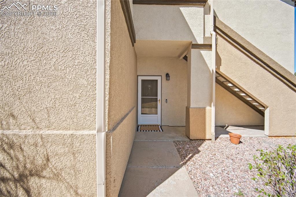 Image 5 of 31: Entryway featuring a white storm door, an exterior wall light, and stucco s