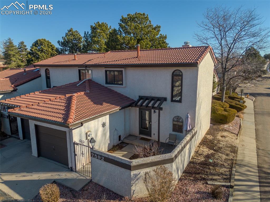 Caption: View of front of home featuring stucco siding, a tile roof, concrete driveway, and a garage