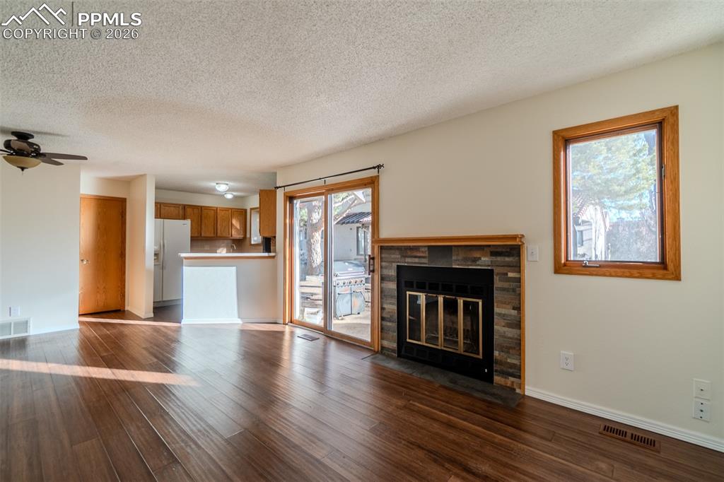 Image 13 of 26: livingroom featuring a fireplace, dark wood-type flooring, and a textured c