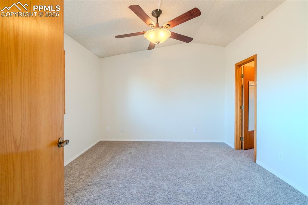 Image 8 of 26: Spare room with lofted ceiling, carpet, and ceiling fan