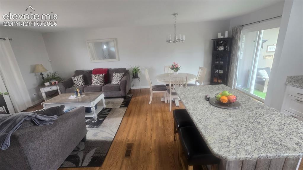Image 2 of 43: Hardwood flooring, kitchen island with stone countertop, white shaker style