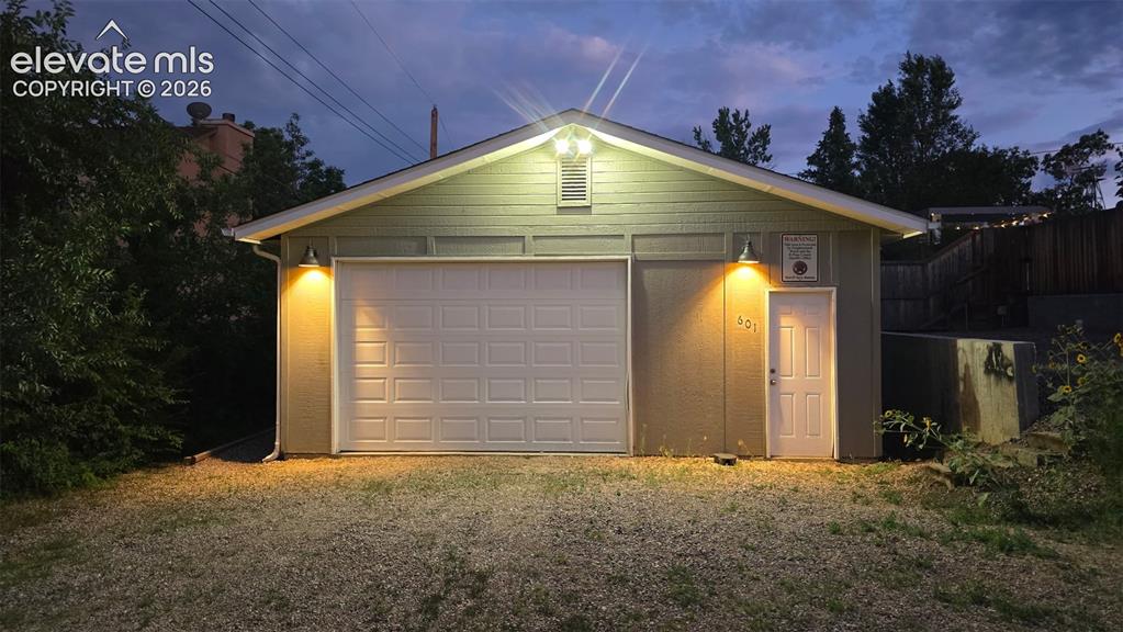 Image 32 of 43: Detached garage structure featuring a paneled overhead door, a pedestrian e