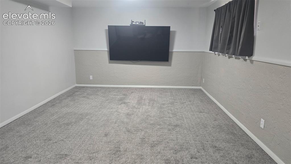 Image 9 of 43: Wall-mounted television with gray textured wainscoting and light gray carpe