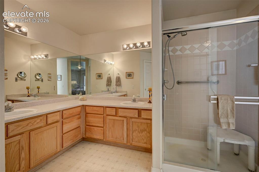 Image 26 of 50: Primary Bathroom with dual vanity and shower view.