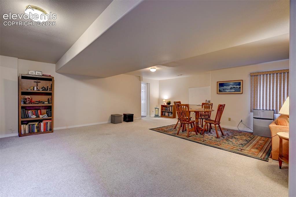 Image 33 of 50: Huge basement room area with card/game table area. Carpet.