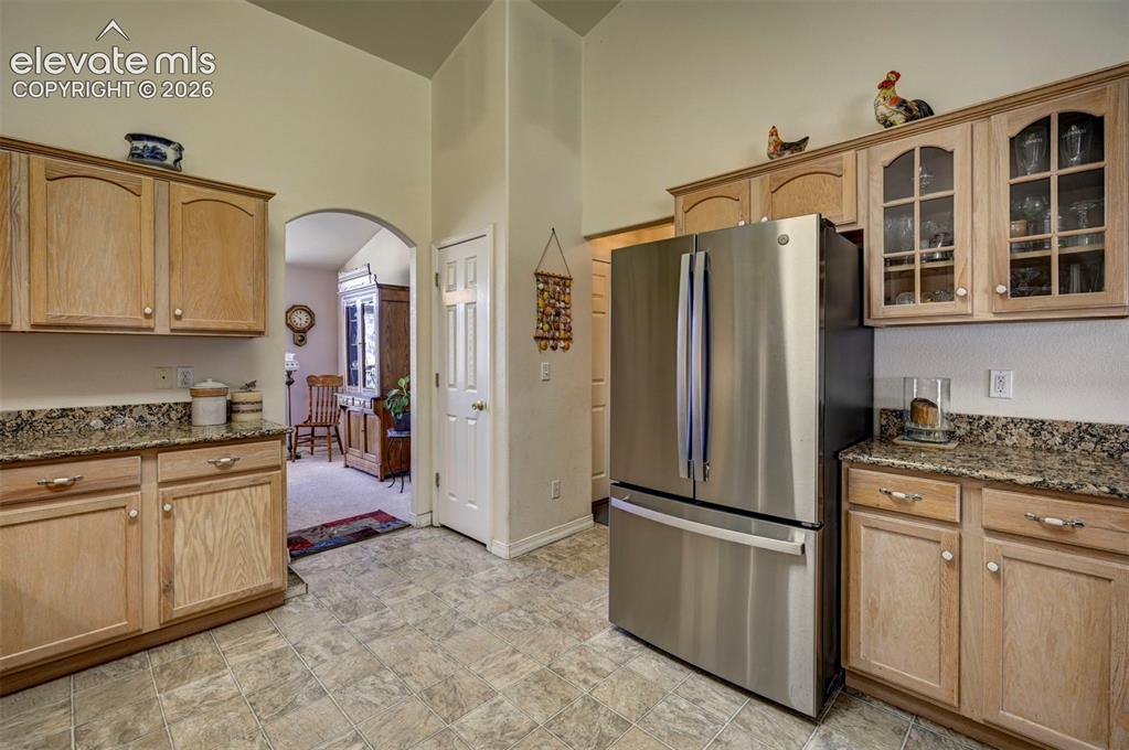 Image 9 of 50: Kitchen area with wood finish cabinets some with glass doors, granite count