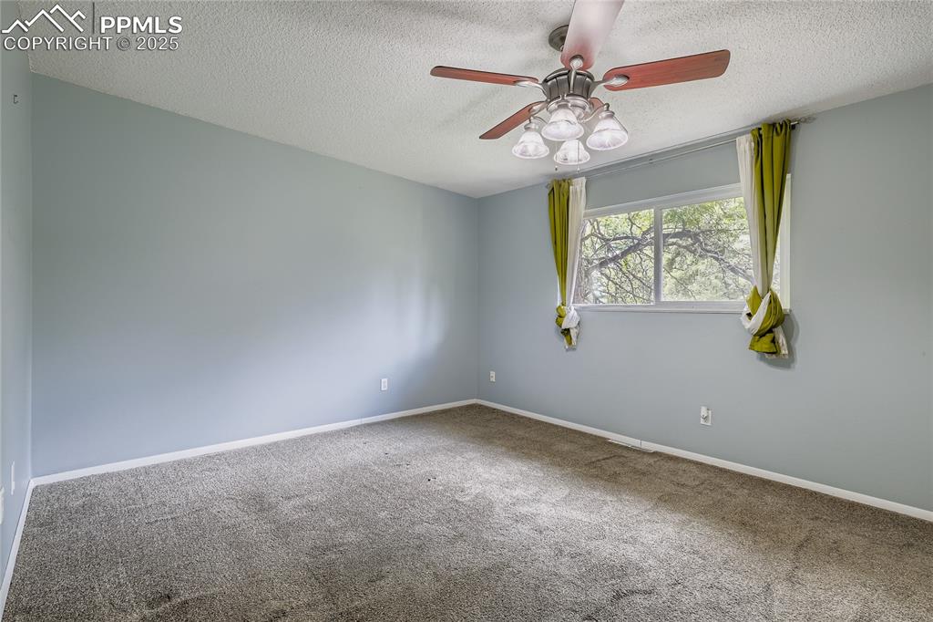 Image 11 of 28: Carpeted spare room featuring a textured ceiling and a ceiling fan